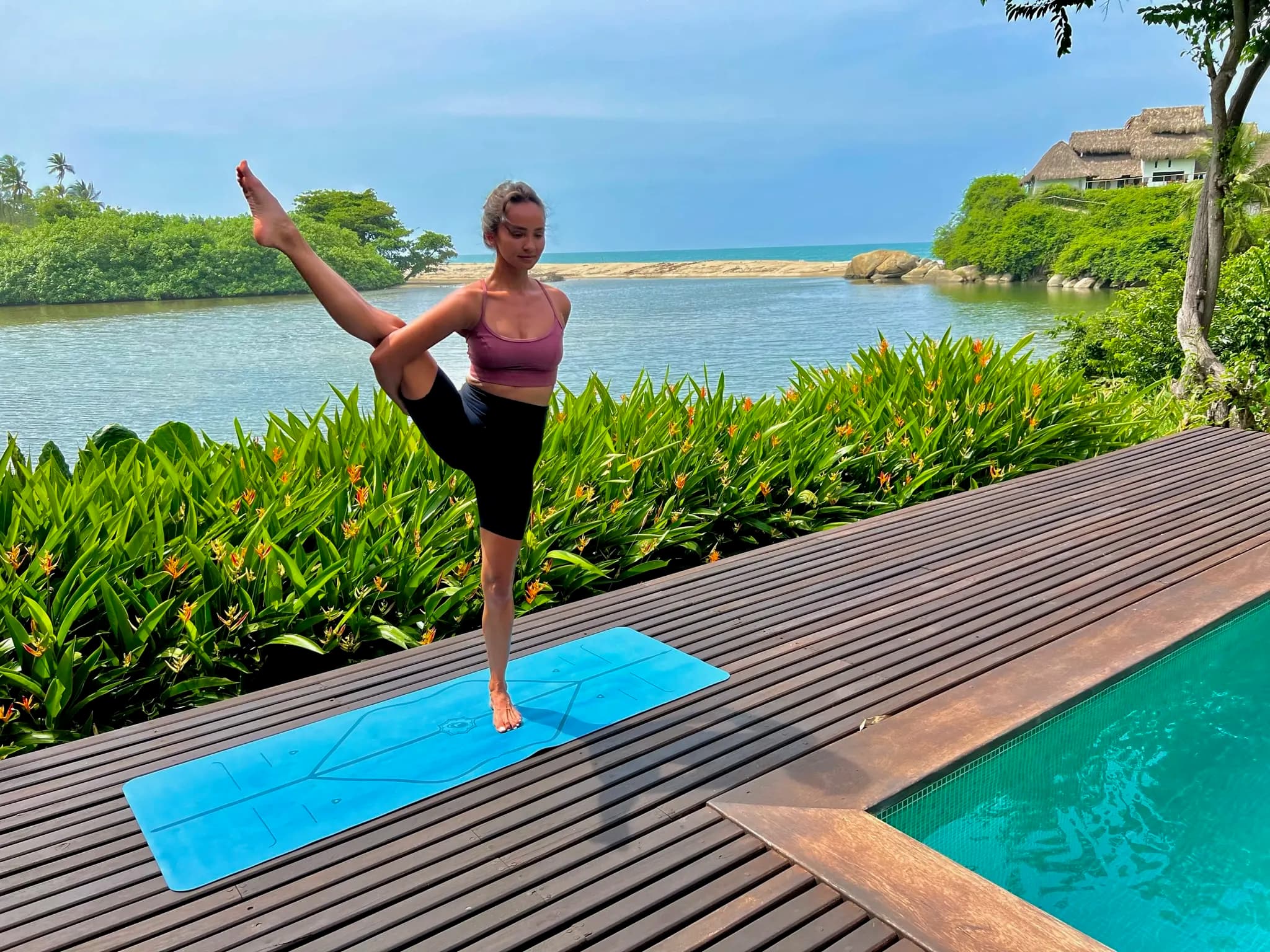 Postura del bailarín al borde de una piscina, con la laguna atrás.