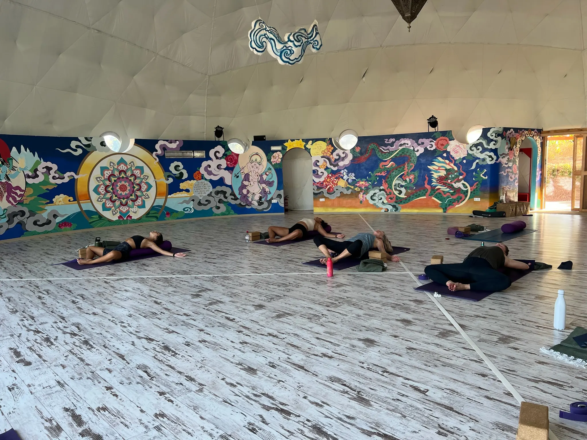 Savasana en una sala con murales de colores en las paredes.