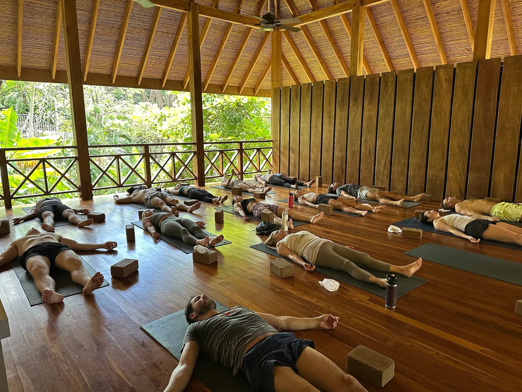 Savasana al final de la clase, en una shala de madera abierta al jardín.